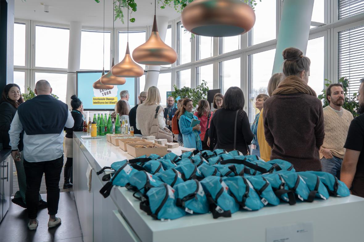 Mehrere WienIT-Bauchtaschen liegen auf der Bar, im Hintergrund Menschen, die sich unterhalten. 